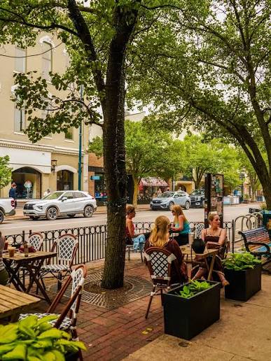Sidewalk café seating under leafy trees along Front Street